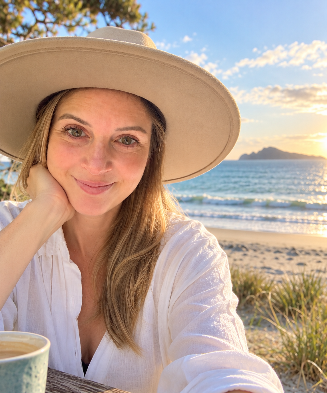 Steph smiling in a sun hat at the beach